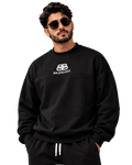 A man wearing a black Balenciaga crewneck sweatshirt and matching black sweatpants with white drawstrings, posed against a dark gray studio background.