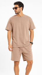 طقم رجالي كاجوال بلون بيج مكون من قطعتين: تيشرت قطني فضفاض (Oversized) بياقة دائرية وشورت متناسق برباط خصر، يظهر بتصميم عصري مريح على خلفية بيضاء.