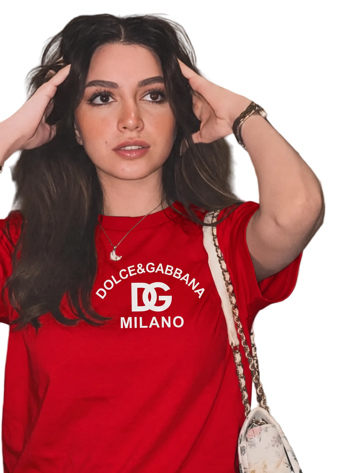 A woman wearing a red Dolce & Gabbana Milano t-shirt with a white logo print, posing with a patterned shoulder bag against a modern beige wall.