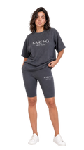 Woman wearing a dark gray 'Kareno New York' t-shirt and shorts on a white background