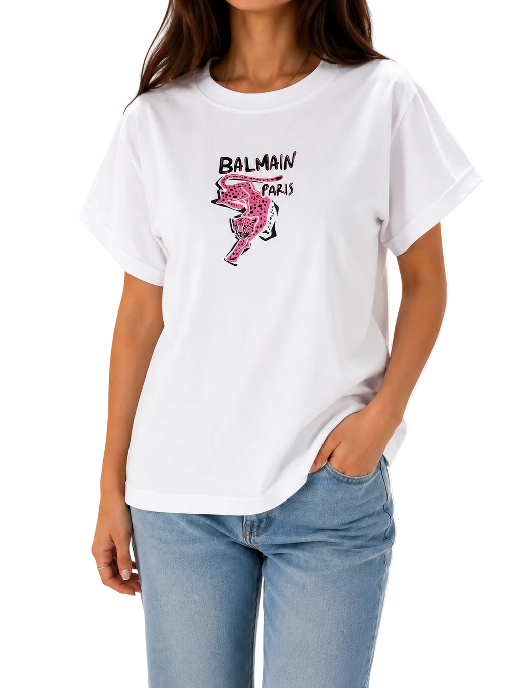 A woman wearing a white Balmain Paris graphic t-shirt with a pink flamingo print and black logo text, paired with light blue jeans, against a plain white background.
