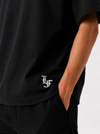 Male model wearing a black oversized premium cotton t-shirt with embroidered white LF logo on a clean white studio background.