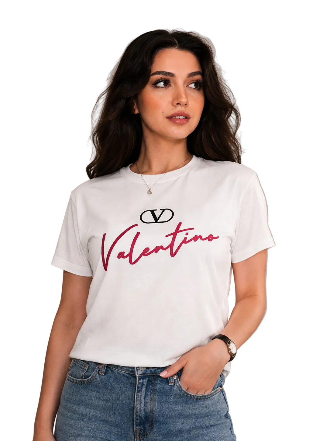 A woman wearing a white short-sleeve t-shirt with a red and black Valentino logo graphic on the front, paired with blue jeans, standing against a neutral beige paneled wall.