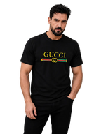 A man wearing a black Gucci t-shirt with a yellow logo and green and red stripe detail on the chest, posed against a neutral gray background.