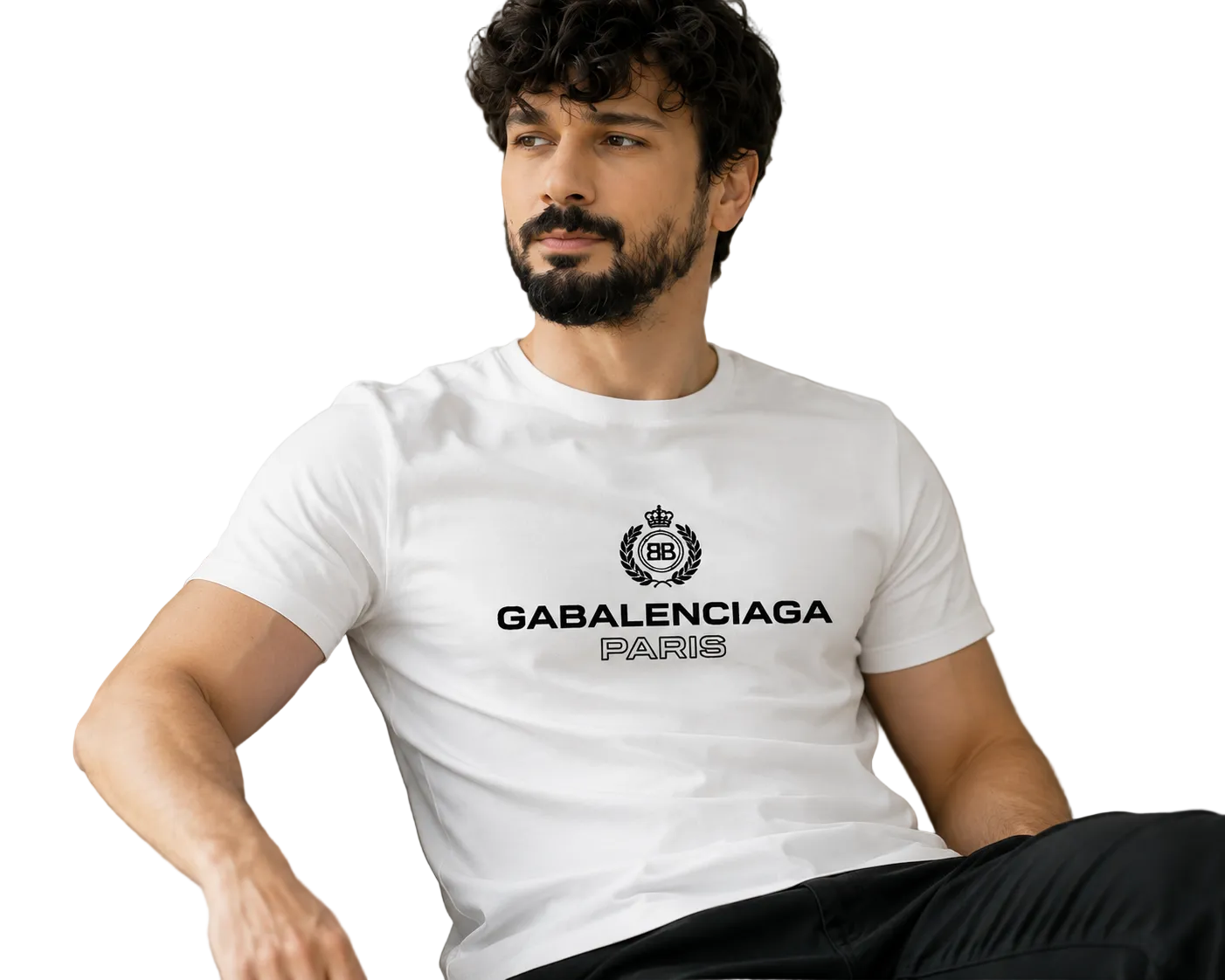 A man with a beard and curly hair sits on a beige sofa wearing a white Balenciaga Paris t-shirt with a black printed logo and text.