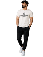 A man wearing a white crew-neck t-shirt with a black 'GABALENCIAGA PARIS' logo, paired with black pants and white sneakers, standing in a modern indoor setting.