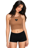 A woman modeling a ribbed brown cropped tank top with a small black triangular chest logo, paired with black shorts, against a plain light gray studio background.