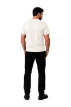 A man viewed from behind wearing a plain white short-sleeve t-shirt and black pants, standing against a neutral gray studio background with soft shadow patterns.