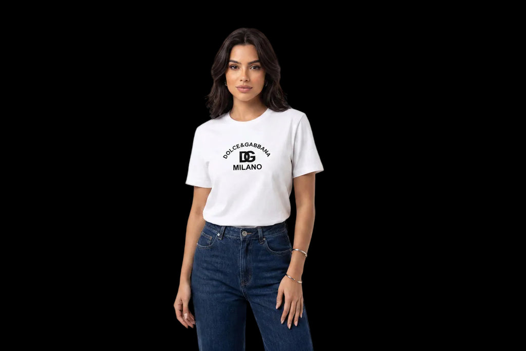 A woman modeling a white short-sleeve t-shirt with a black 'DOLCE&GABBA MILANO' logo printed on the chest, paired with dark blue jeans, against a plain white studio background.