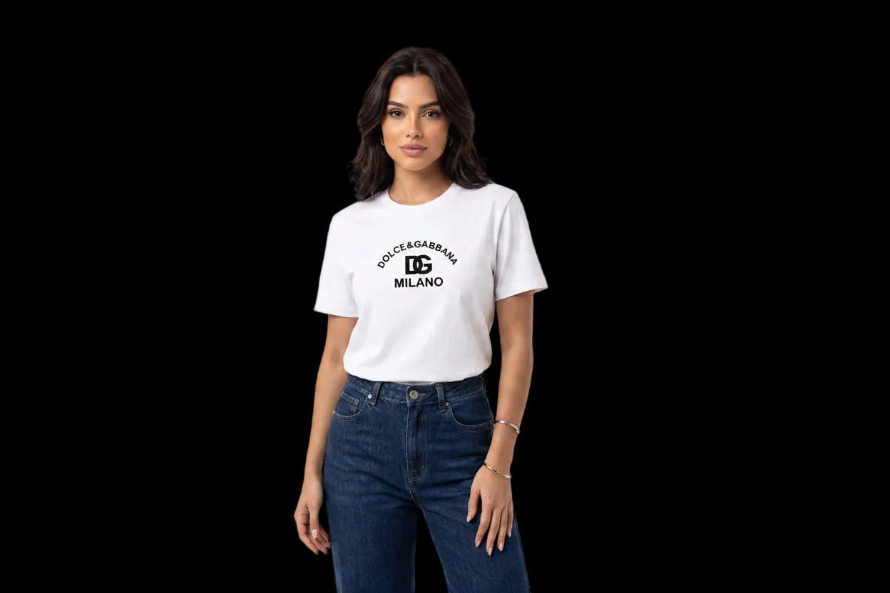 A woman modeling a white short-sleeve t-shirt with a black 'DOLCE&GABBA MILANO' logo printed on the chest, paired with dark blue jeans, against a plain white studio background.