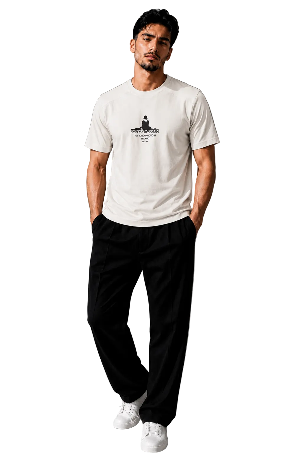 A man wearing a white crew-neck t-shirt with a black graphic print on the chest, paired with black pants and white sneakers, standing in a modern gray room.