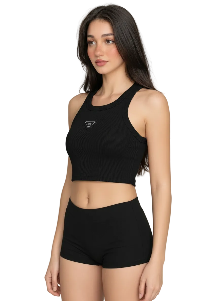 A woman modeling a black ribbed athletic crop top and matching high-waisted shorts against a plain light gray studio background.