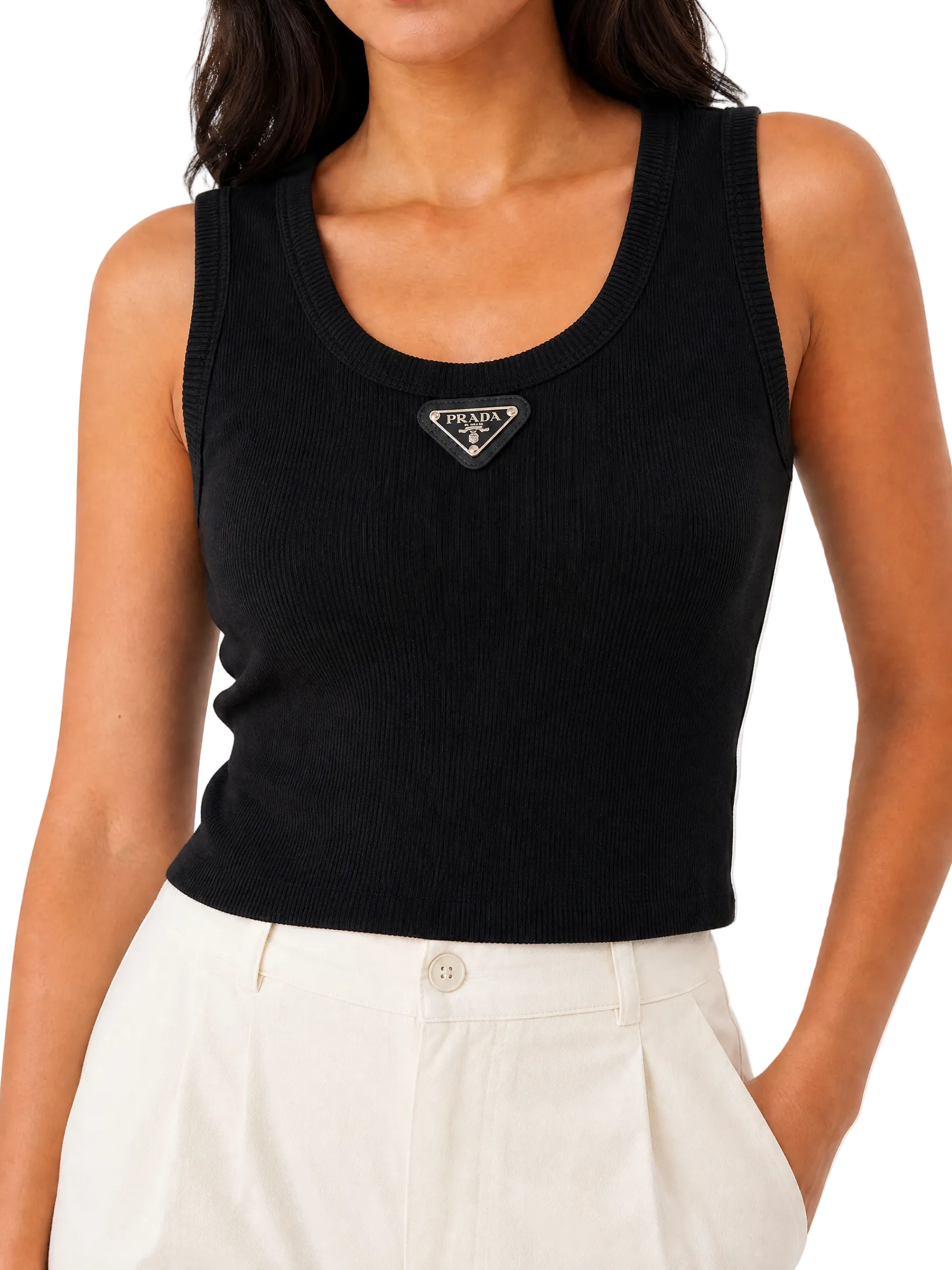 A close-up of a model wearing a black ribbed knit scoop-neck tank top with a small silver-tone Prada logo patch on the chest, paired with off-white trousers.