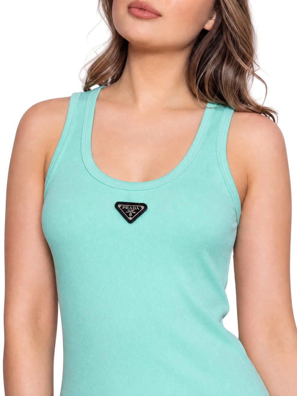 A close-up of a woman wearing a mint green ribbed tank top with a black triangular Prada logo patch on the chest, set against a plain white background.