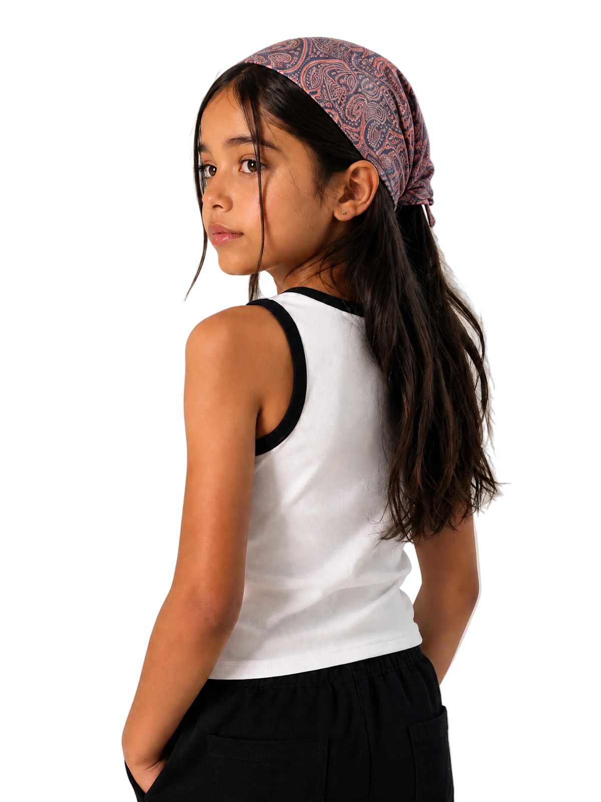 A young girl with long dark hair is shown from the back and side, wearing a white ribbed tank top with black trim, black pants, and a patterned mauve and blue bandana headwrap against a plain light beige studio background.