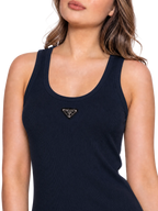 A close-up of a woman wearing a navy ribbed tank top with a small gold-tone Prada triangle logo on the chest, against a clean white background.