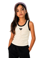 A young girl wearing a cream ribbed tank top with black trim and a black triangle logo patch on the chest, paired with black pants and a purple patterned headband, posing against a neutral textured background.