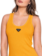A close-up of a woman wearing a ribbed yellow tank top with a small black triangular Prada logo patch on the chest, against a clean white background.