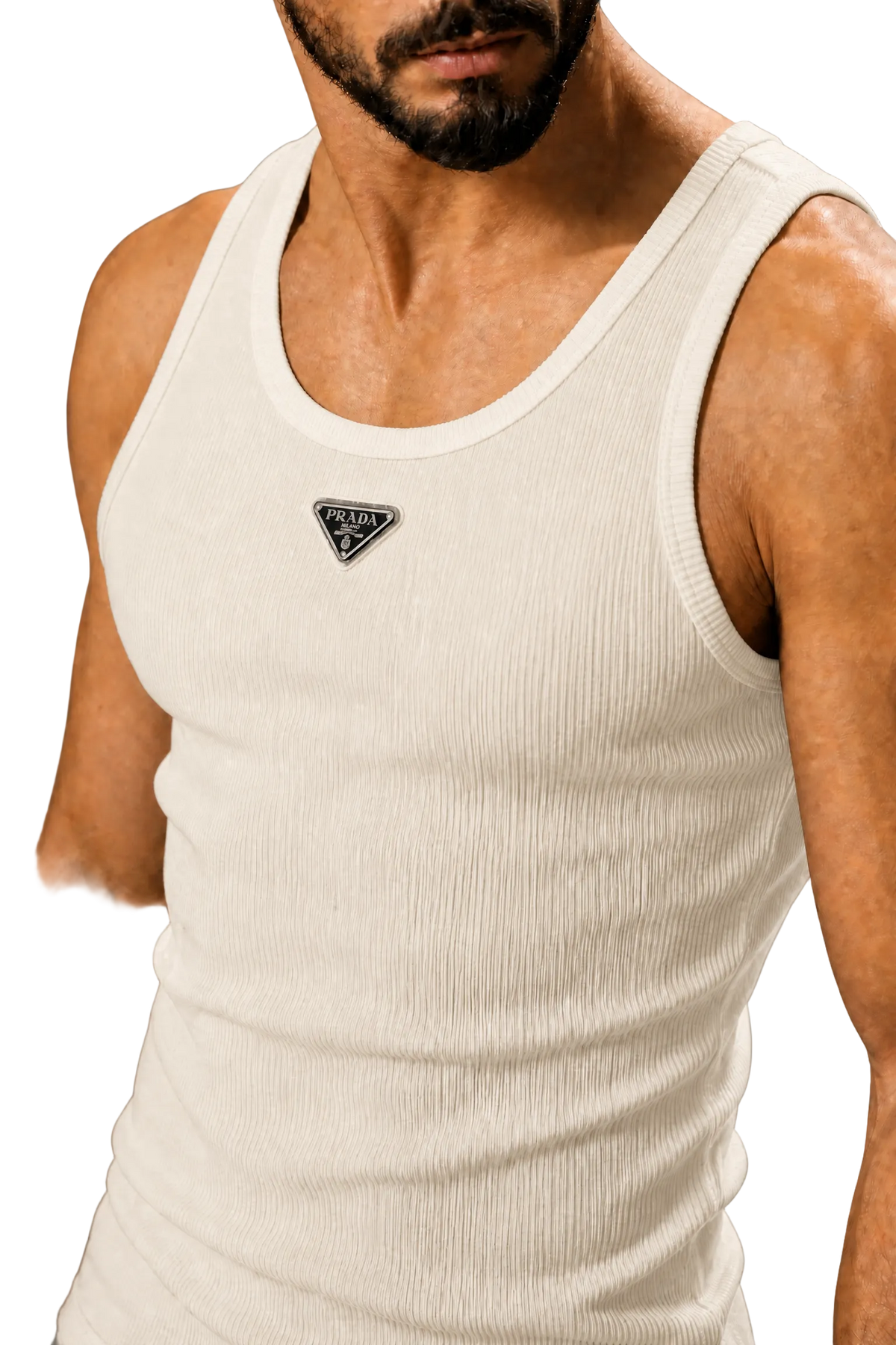A close-up of a man wearing a ribbed cream-colored tank top with a small black triangular logo patch on the chest, set against a neutral gray background.
