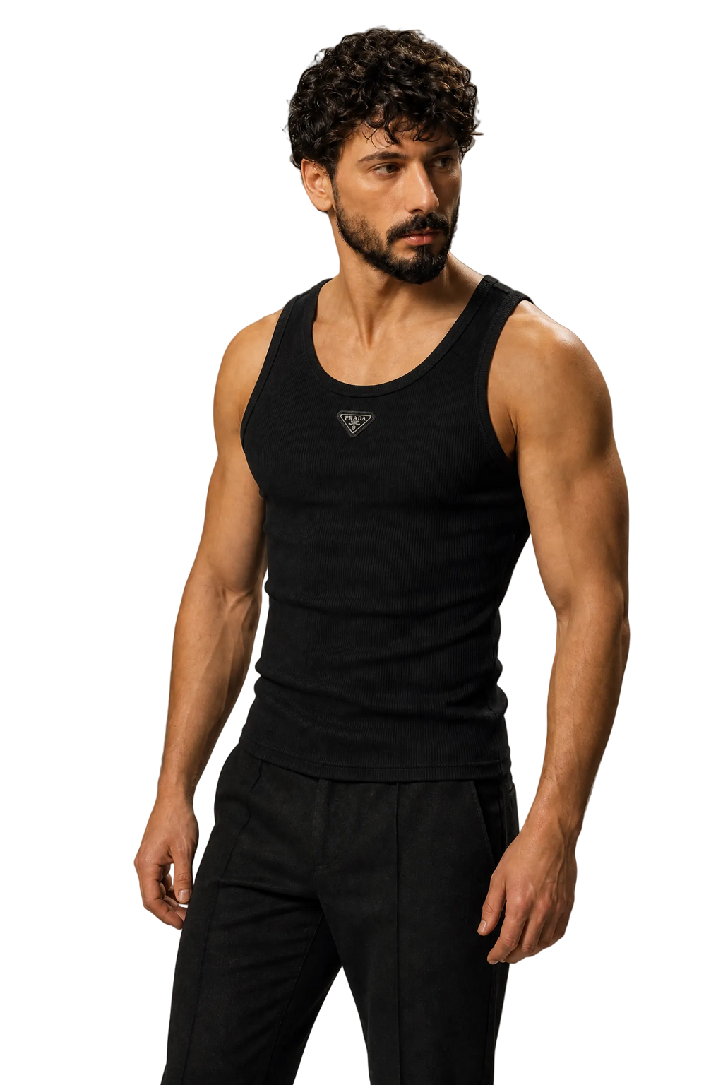 A muscular man with curly dark hair and a beard wearing a black ribbed tank top with a small silver geometric logo on the chest, paired with black pants, against a neutral gray studio background.