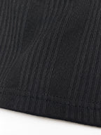 Close-up of a black ribbed knit fabric with a hemmed edge, showing the texture and stitch detail against a white background.
