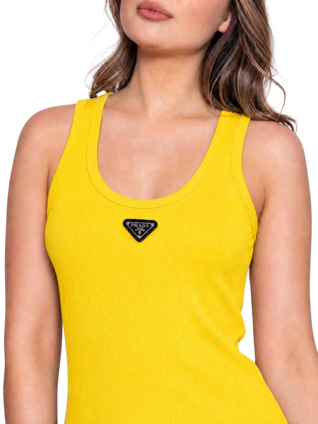 A close-up of a woman wearing a bright yellow ribbed tank top with a black triangular Prada logo patch centered below the neckline, against a plain white background.